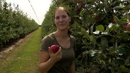 Landwirtin Jacqueline Huhndorf mit einem Apfel vor einer ihrer Apfelreihen.