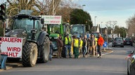 Viele Menschen stehen neben Traktoren. Schilder werden hochgehalten