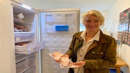 Landwirtin Renate Wolfgarten an einem Kühlschrank, hat Fleisch in den Händen