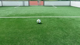 Das Bild zeigt einen Fußball auf dem neuen Kunstrasen. 