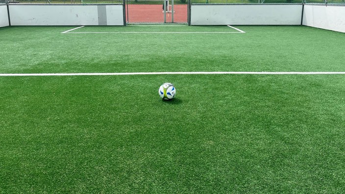 Das Bild zeigt einen Fußball auf dem neuen Kunstrasen. 