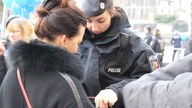 Eine Polizistin kontrolliert die Tasche einer Frau