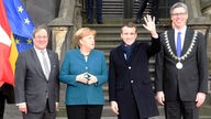 Angela Merkel und Emmanuel Macron umgeben von Polizisten