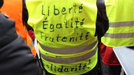 Die Aufschrift Liberté, Égalité, Fraternité, Solidarité auf einer gelben Weste