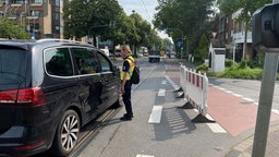 Eine Einsatzkraft erklärt einem Autofahrer an einer Straßensperre das weitere Vorgehen