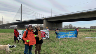 Das Bild zeigt Demonstranten vor der Friedrich-Ebert-Brücke in Bonn, die die geplante Verbreiterung der Brücke kritisieren.