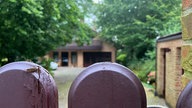 Ein Grundstück mit einem sandsteinfarbenen Backsteinhaus. Fotografiert aus Richtung der Einfahrt