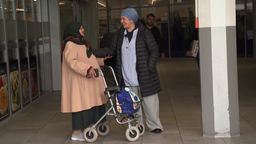 Die Sozialarbeiterin Saloua Mohammed grüßt eine ältere Frau, die mit Rollator durch Bonn-Tannenbusch läuft.