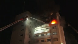 Flammen schießen aus einem Fenster in einem Mehrfamilienhaus in kamp-Lintfort. Die Drehleiter ist ausgefahren und der Brand wird von der Feuerwehr gelöscht.