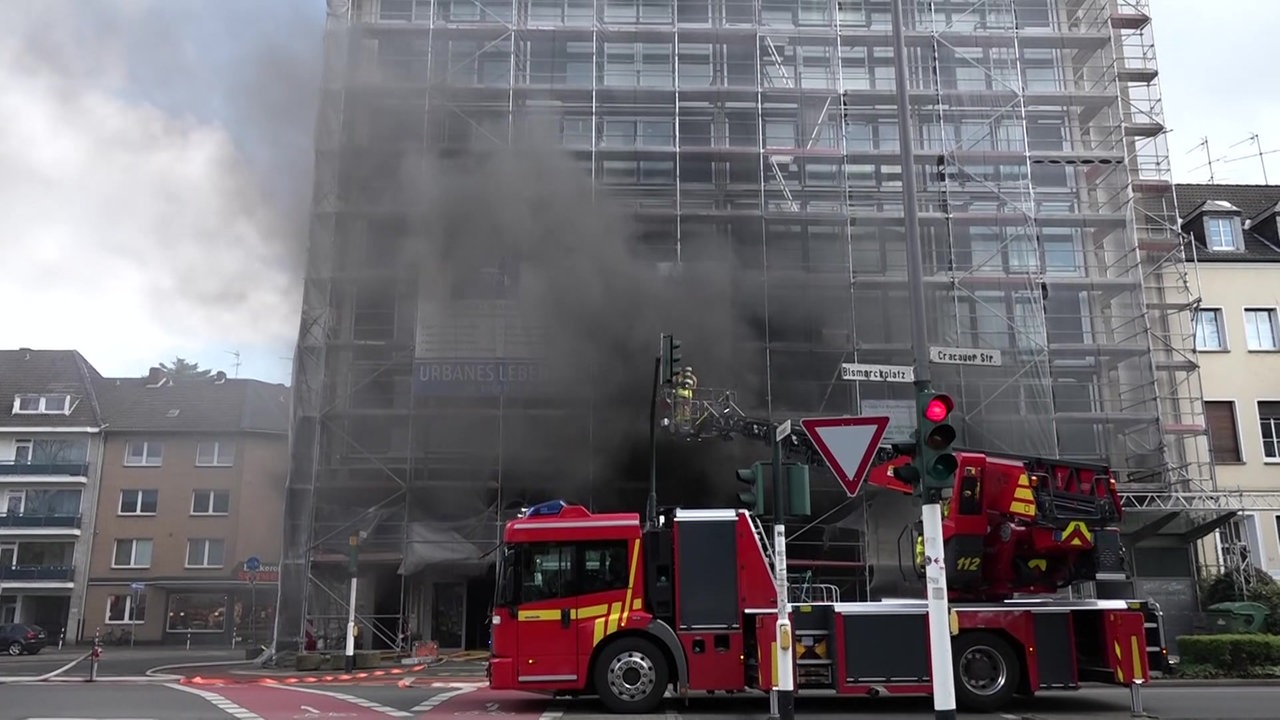 Viel Rauch kommt aus einem Gebäude im Gerüst. Davor steht ein Feuerwehrauto