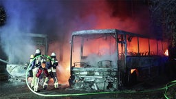 Feuerwehrleute löschen zwei brennende Reisebusse in Düsseldorf-Benrath.