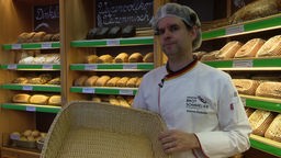 Bäcker Johannes Dackweiler steht in seiner Bäckerei und hält einen leeren Brotkorb.