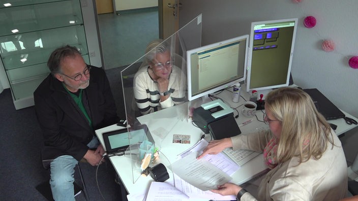 Drei Menschen sitzen am Schreibtisch im Bürgerbüro