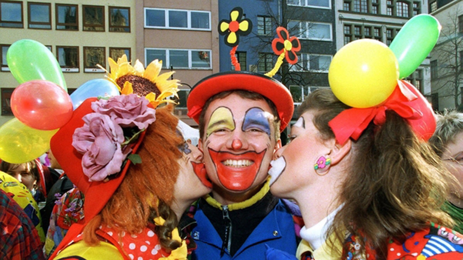 Clown erhält von zwei Clowndamen ein Bützchen