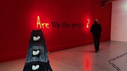 an einer roten Wand steht: Are We the people?