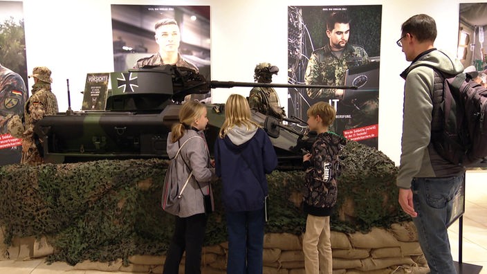 3 Kinder und ihr Vater vor dem von der Bundeswehr aufgestellten Panzer im Einkaufszentrum