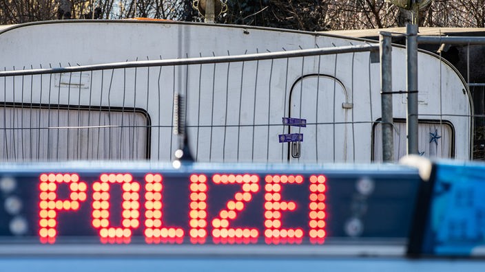 Ein Polizeiauto steht vor einem abgesperrten Wohnwagen auf dem Campingplatz Eichwald in Lügde