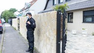 Ein Polizist steht vor einer Villa in Leverkusen