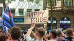 Ein Mann hält ein Schild mit der Aufschrift "Happy Pride" hoch