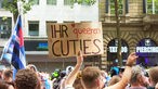 Ein Mann hält ein Schild mit der Aufschrift "Ihr queeren Cuties" hoch