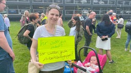 Erzieherin und Mutter Sarah Wiesner steht bei der Demo mit einem Plakat vor dem Landtag 