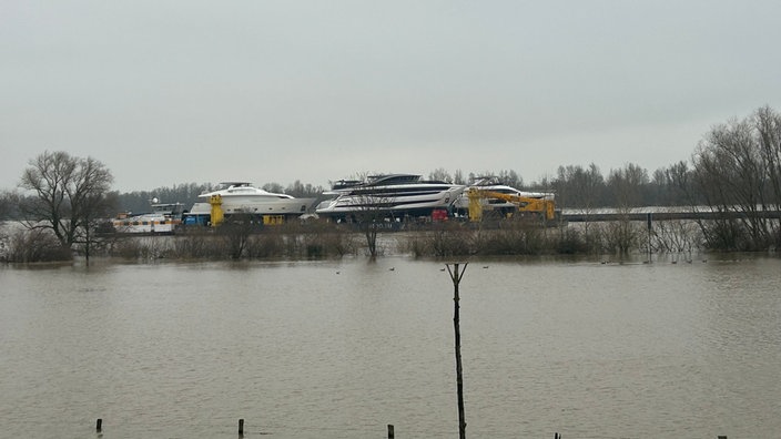 Yachten auf einem Lastenschiff im Hochwasser des Rheins