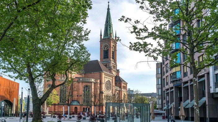 Evangelische Johanneskirche auf dem Martin-Luther-Platz in Düsseldorf, eine Kirche mit braunen Ziegeln und olivgrünen Dächern.