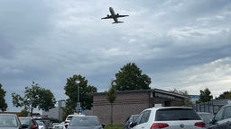 Ein Flugzeug fliegt über einen Einkaufsladen-Parkplatz.