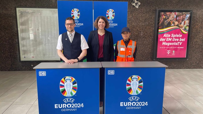 Bahnhofsmanagerin Sonja Kosche und zwei Mitarbeiter der Bahn stehen hinter dem neuen Welcome Desk im Düsseldorfer Hauptbahnhof