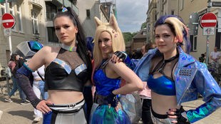 Drei junge Frauen tragen blaue Cosplay-Kostüme.