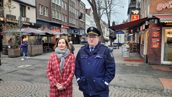 Zu sehen sind eine Frau und ein männlicher Polizist in der Düsseldorfer Altstadt.