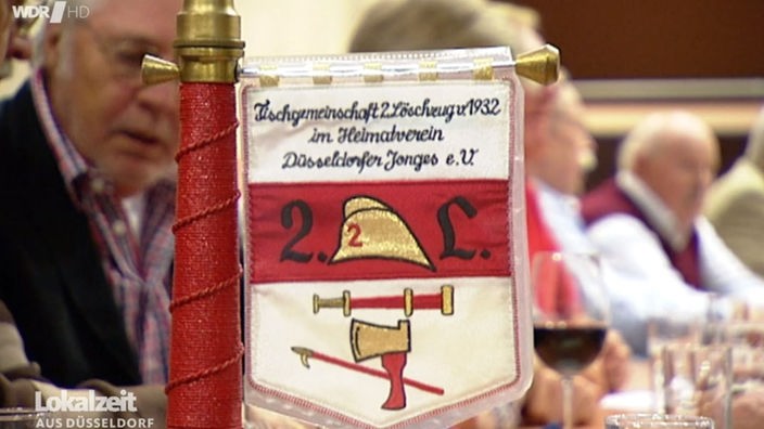 Beim Treffen der Düsseldorfer Jonges steht ein rot-weißer Wimpel der Tischgemeinschaft auf dem Tisch