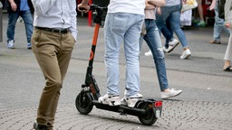 Ein Mann fährt auf einem E-Scooter in einer Fußgängerzone in Köln