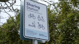 Infotafel Mit der Aufschrift "Sharing Station" und den Abbild von einem Fahrrad, E-Roller und E-Scooter