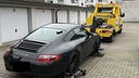 Ein Porsche wird von einem gelben Abschleppwagen weggefahren