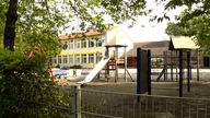 Der Schulhof und das gelbe Don-Bosco-Schulgebäude in Langenfeld von außen.