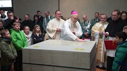 Der Bischof salbt den Altar, einen Quader aus Beton