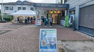 Vor dem Krankenhaus sind Pavillions aufgebaut, der Schriftzug "St. Willibrord-Spital" ist über dem Eingang zu lesen, daran hängen Luftballons