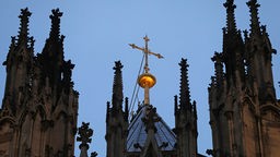 Symbolbild: Ein Kreuz steht hinter dem Strebewerk am Dom.