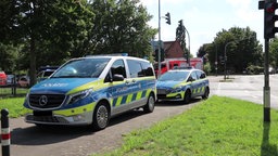 Zwei Polizeiwagen und ein Feuerwehrauto in Köln nach dem Angriff auf zwei Polizisten bei einer Kontrolle.