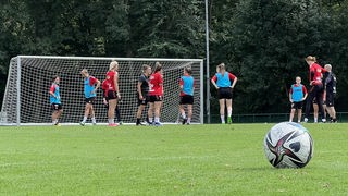 Mehrere Frauen spielen in Trikots Fußball