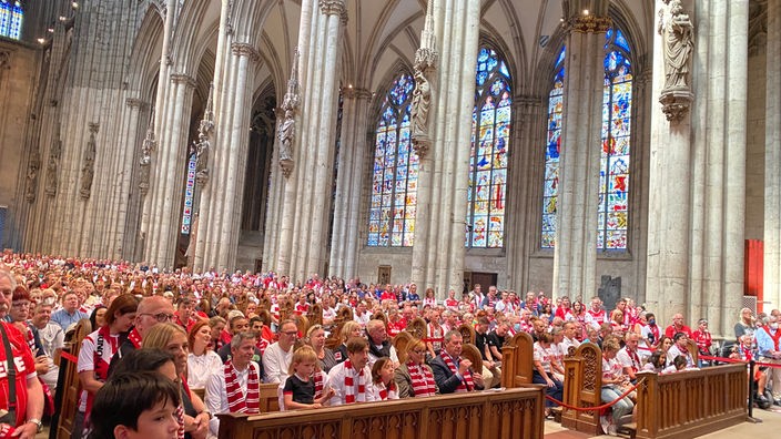 Im Kölner Dom sitzen viele Menschen und verfolgen den Gottesdienst