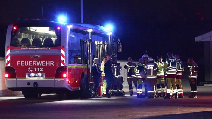 Feuerwehrbus mit Blaulicht und Einsatzkräfte versammelt davor