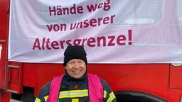 Feuerwehr-Mann Frank Glinski aus Bonn steht bei der Mahnwache vor einem alten Löschfahrzeug mit Banner