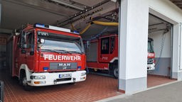 Zwei Feuerwehrfahrzeuge in einem Feuerwehrhaus