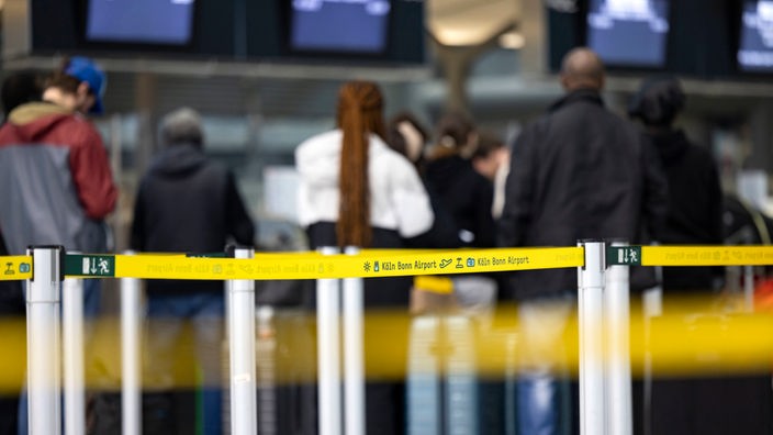 Reisende stehen am Check-In-Schalter