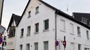 Ein weißes Mehrfamilienhaus mit schwarzem Dach