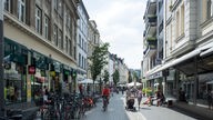 Menschen in der Fußgängerzone Friedrichstraße. Geschäfte, Fahrradfahrer und Fahrräder sind zu sehen.