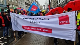 Mehrere Menschen halten großes Banner mit Aufschrift "Justizbehörden Essen - ver.di - Bezirk Ruhr-West"