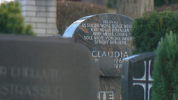Auf dem Bild ist ein Grabstein auf einem Friedhof abgebildet. 
